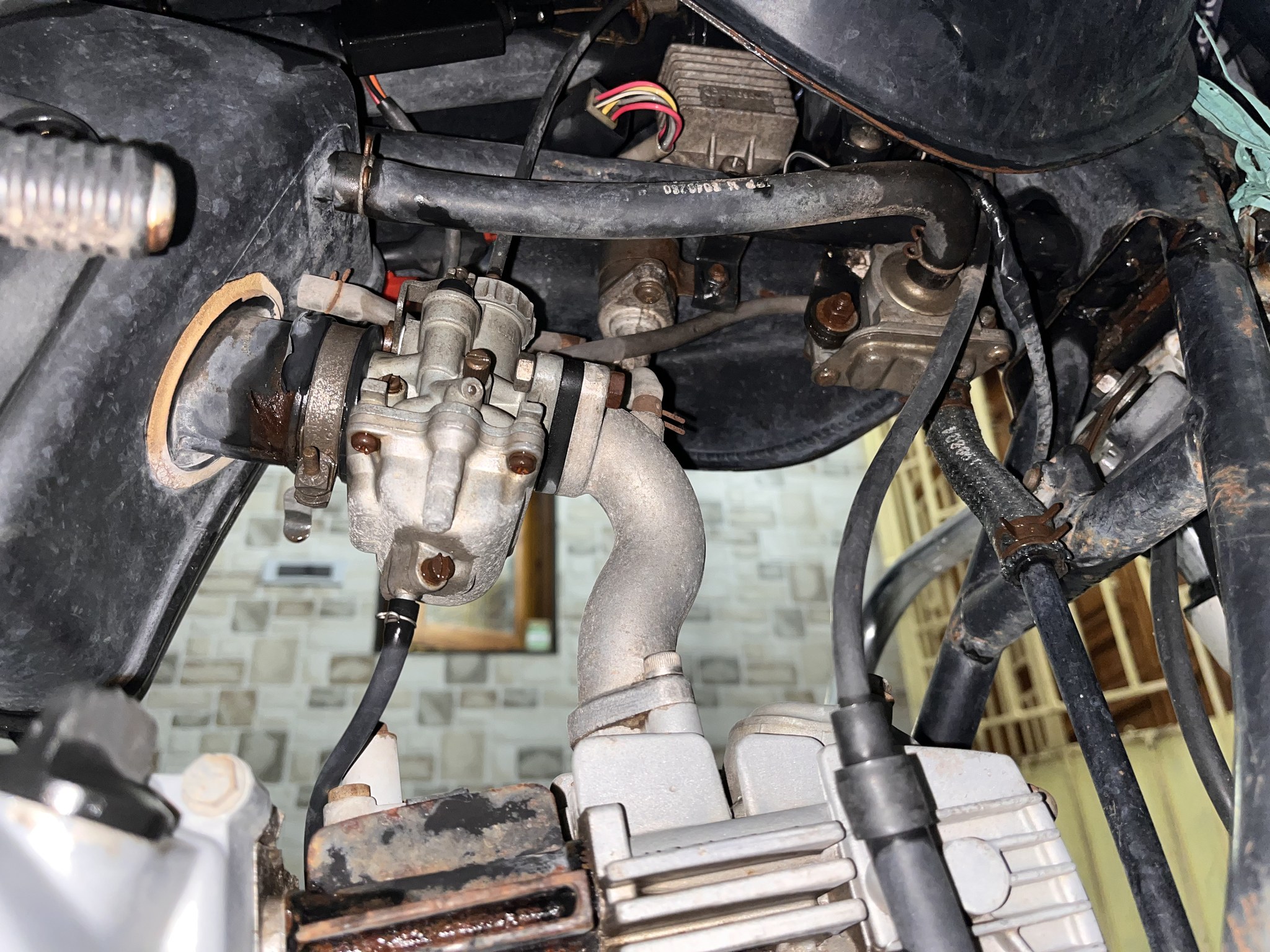 Rusty carburetor and wiring on mounted engine